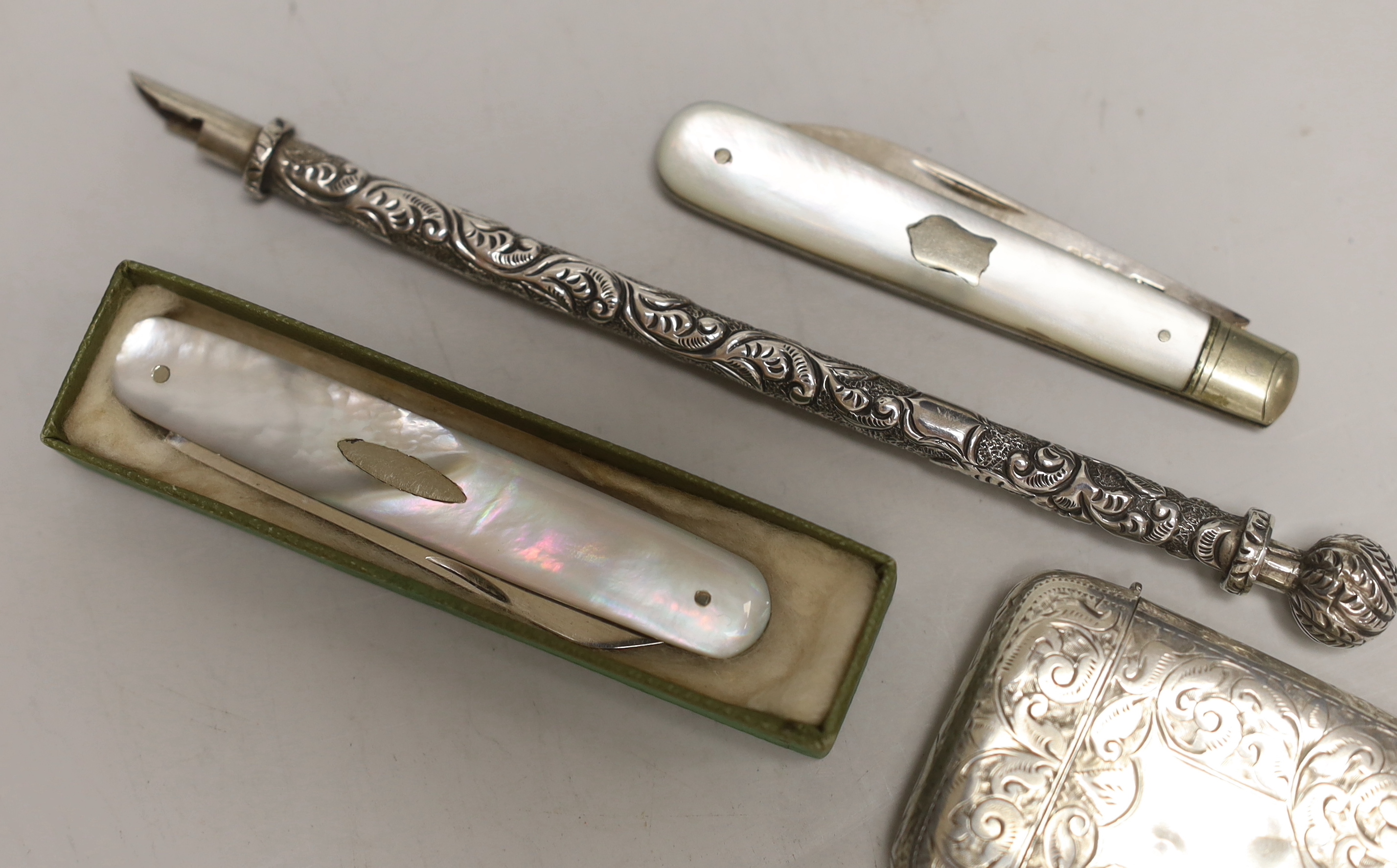 A late Victorian engraved silver vesta case, 53mm, two mother of pearl mounted silver fruit knives and a white metal dip pen.